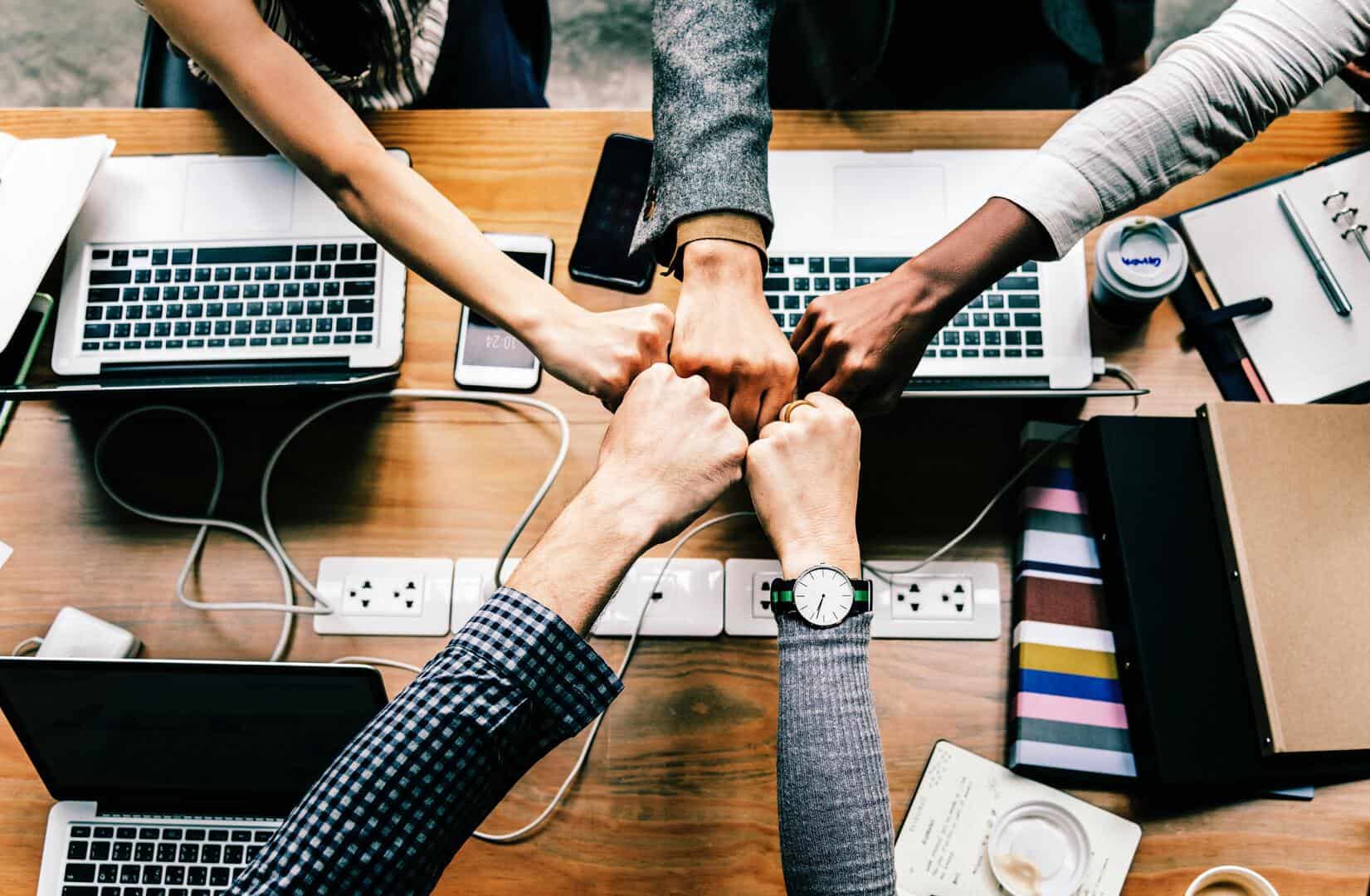 Colleagues fist-bumping at desk, working collaboratively