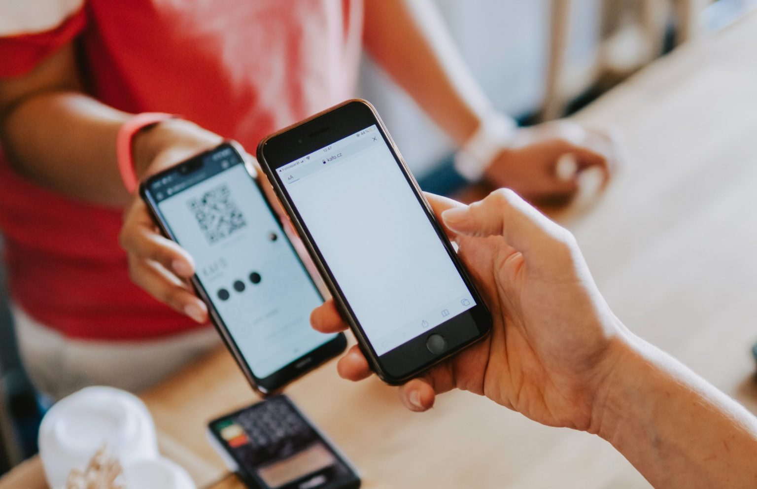 A customer's mobile phone scanning the QR Code shown by a merchant's phone