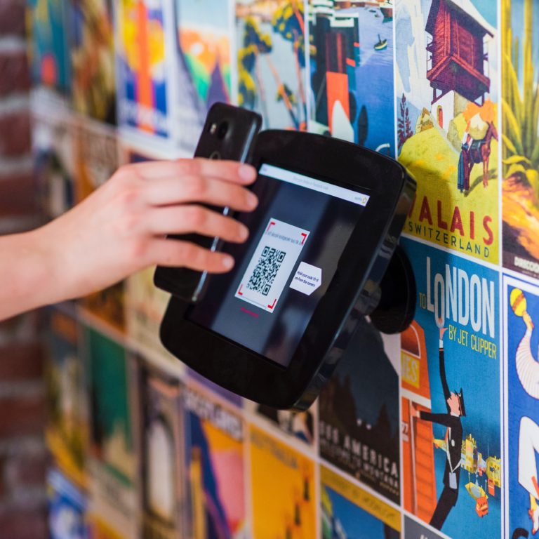 A person scanning the QR Pay code presented on a terminal mounted on a wall